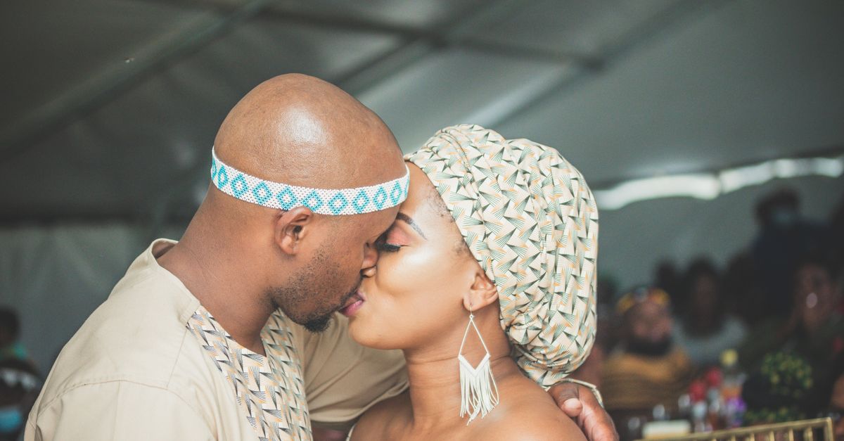 A couple shares a heartfelt kiss at their cultural wedding, reflecting love and tradition.