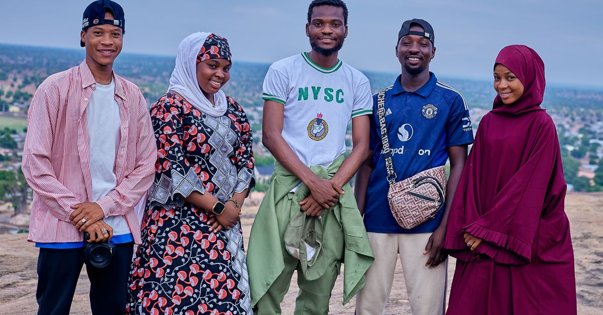 Five young adults smiling outdoors on a rocky landscape under a blue sky.
