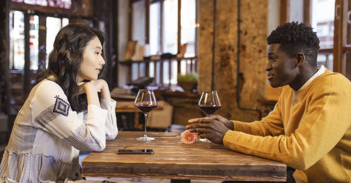 A couple enjoying a romantic date in a cozy café with wine and engaging conversation.