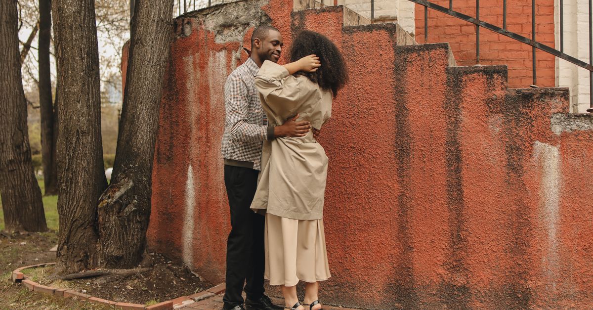 African American couple hugging near a rustic staircase outdoors, showcasing love and togetherness.