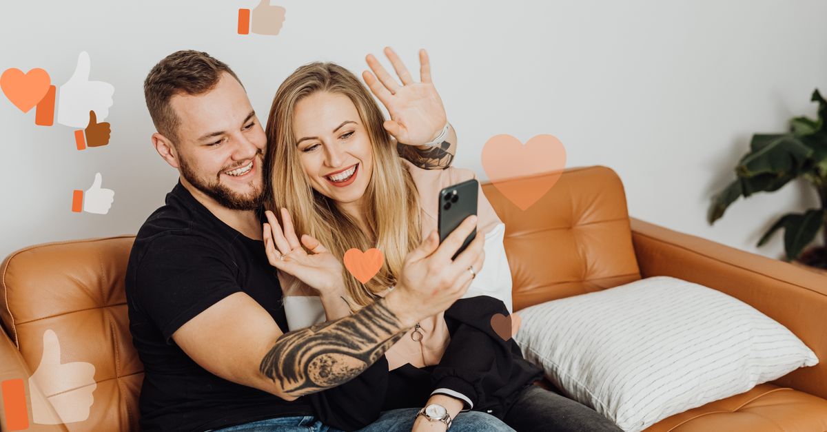 A smiling couple takes a selfie video call at home with digital social media icons overlay.