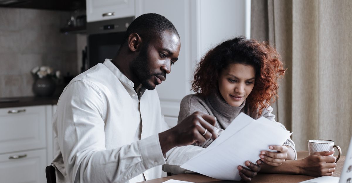 Couple working together on documents at home interior using a laptop.