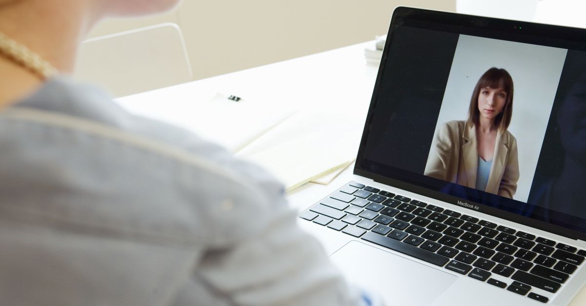 Close-up of woman on a video call using a laptop in a modern workspace.
