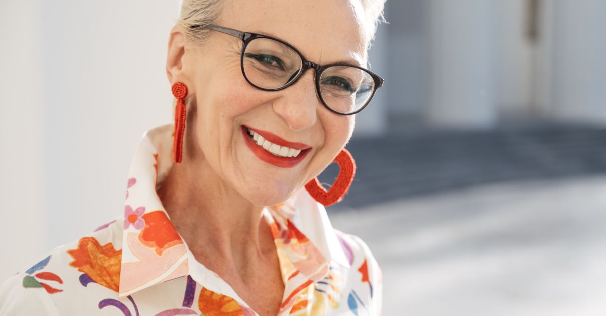 Smiling senior woman in a floral shirt with eyeglasses, exuding warmth and confidence.