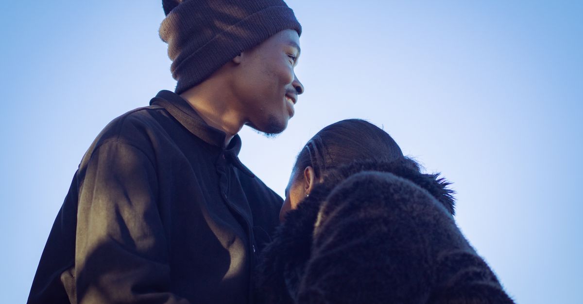 A tender moment between a young couple in Nairobi, reflecting love and warmth under a clear blue sky.